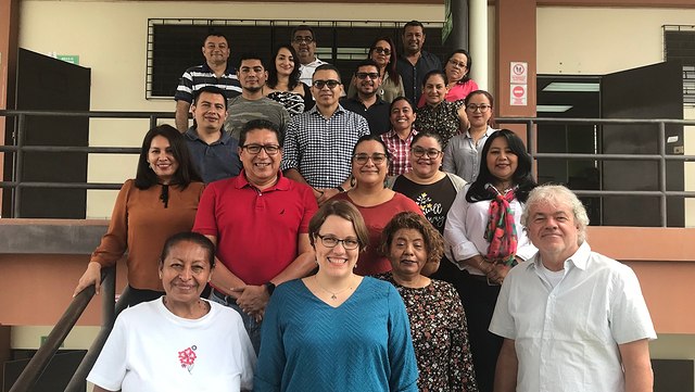 22 Personen, auf einer Treppe in Reihen aufgestellt, die Lächelnd in die Kamera blicken