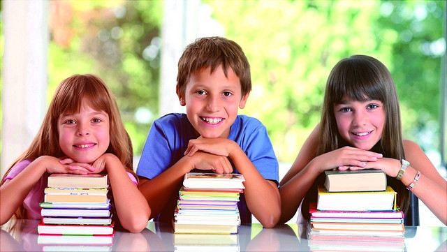 Drei Kinder, gestützt auf Bücherstapel
