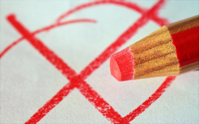 Ein Kreuz auf einem Wahlzettel und ein rotes Stift.